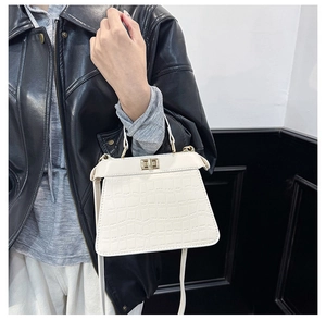 Detalle del bolso blanco con grabado de cocodrilo, herrajes dorados y cierre giratorio