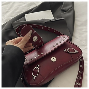 Dettaglio della borsa sottobraccio in pelle bordeaux con rivetti argento e chiusura magnetica