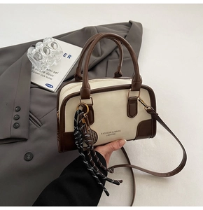 Detail view of retro bowling-style handbag on gray suit with decorative rope charm