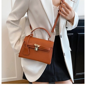 Brown lychee leather Kelly bag detail with gold metal padlock and crossbody strap