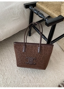 Detailed view of the embossed logo on the leopard print tote bag with brown velvet texture
