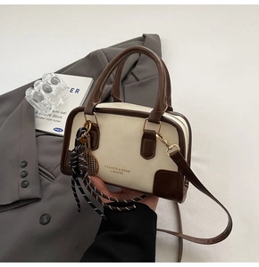 Detailed shot of retro Boston bag with tennis racket charm on grey blazer background