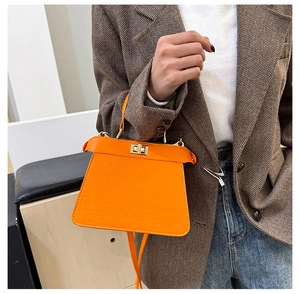 Gros plan du mini sac à main orange à motif crocodile avec fermoir rotatif doré