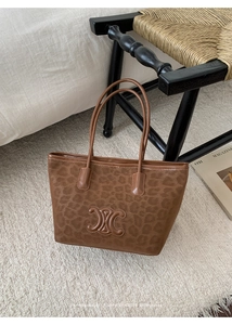 Detail of vintage leopard print tote bag with embossed metal emblem on plush carpet