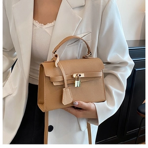 Detailed close-up of camel leather Kelly style bag with lychee grain and gold clasp