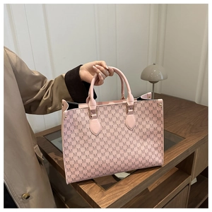 Close-up of pink tote bag with M-pattern jacquard and leather handles in a chic room