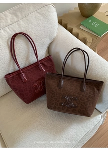 Close-up of leopard print tote bags with embossed logo detail and leather handles