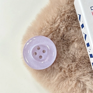 Macro shot of purple glitter button phone grip on a soft textured background