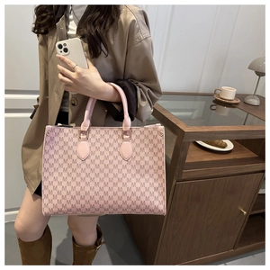 Detail of pink tote bag with M-pattern lettering texture and leather handles