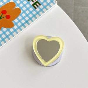 Detail of a light yellow heart-shaped mirror phone socket on a white surface