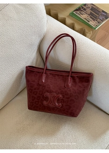 Detail of dark red leopard print tote bag with metallic logo on beige sofa
