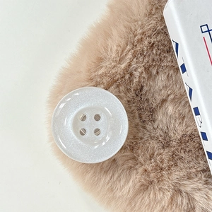 Macro shot of white pearlescent 4-hole button on faux fur texture detail