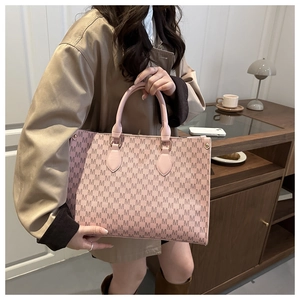 Detail of pink tote bag with M-letter pattern and golden hardware in a home setting