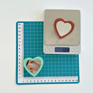 Detail showing heart-shaped phone mirrors weighing 12.4g with 50mm diameter dimensions