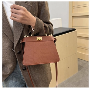 Sac à main marron avec gaufrage crocodile et fermoir doré porté par un mannequin