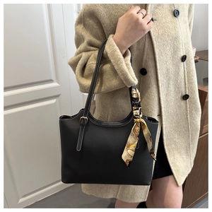 Detail of black leather tote bag with white stitching and silk scarf on handle