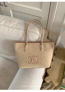 Detail of leopard print tote bag with embossed emblem on white fabric background