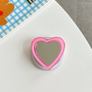 Macro view of a pink heart-shaped phone grip with built-in mirror and frosted edges