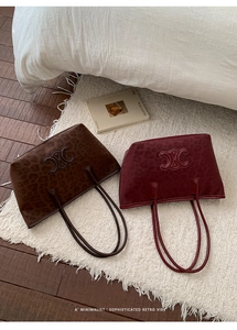 Close-up of retro leopard print tote bags in dark brown and wine red with embossed logo