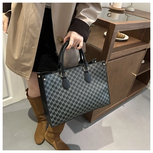 Detail of printed large tote bag with M-pattern and gold hardware in a cafe setting