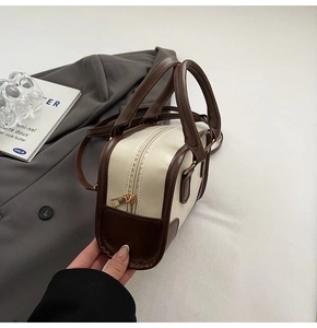 Detailed shot of two-tone contrast shoulder bag with brown handles and cream PU leather