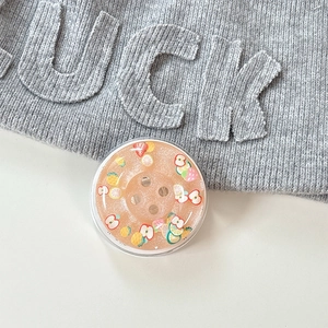 Detail of round orange glitter phone grip with embedded colorful mixed fruit slices