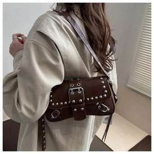 Dettaglio borsa sottobraccio in pelle marrone vintage con borchie punk e fibbia metallo
