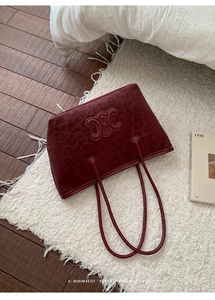 Detail of dark red leopard print suede tote with embossed logo and slim top handles