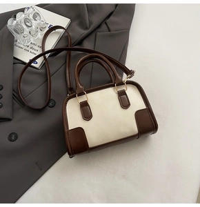 Detail of vintage contrast color stitching on a cream and brown retro handbag