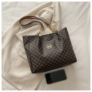Détail du sac cabas marron à motif M avec chaîne dorée et logo métallique