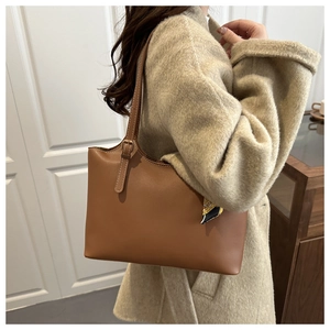 Detail view of brown leather tote bag with metal buckle and decorative silk scarf