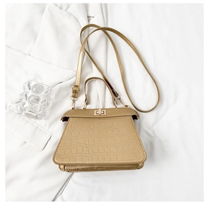 Détail rapproché du motif crocodile champagne sur un sac à main à bandoulière