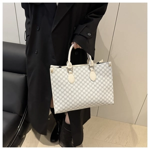 Detail of white tote bag with all-over M-letter print and cylindrical handle