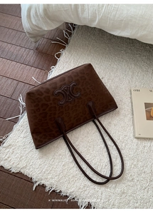 Detailed view of leopard print tote bag with embossed logo on soft textured fabric