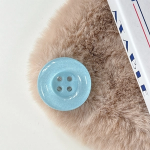 Close-up of a light blue glitter resin button phone grip on a brown fur texture surface