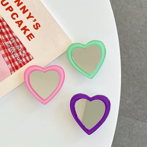 Detail view of heart-shaped portable makeup mirrors in pink, green, and purple colors