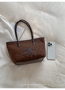 Close-up of leopard print tote bag with brown leather handles and brand logo detail