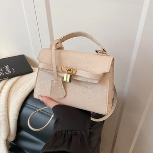 Elegant beige lychee texture leather handbag with gold lock shown in a lifestyle setting