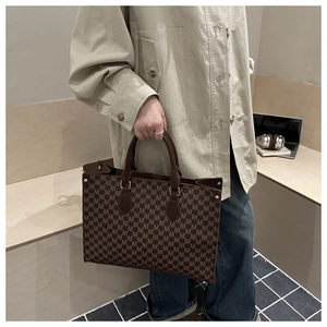 Detail of retro tote bag featuring dark brown M-letter monogram and leather handles
