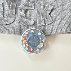Macro view of blue glitter button phone grip with colorful fruit charm details