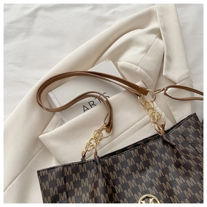 Détail du sac cabas à motif M avec chaîne dorée posé sur un blazer blanc pur