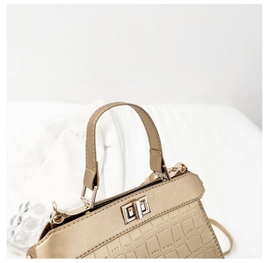 Gros plan d'un sac à main doré motif crocodile avec fermoir rotatif en métal poli