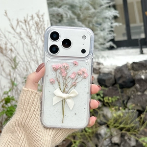 Detailed view of iPhone case with pink dried flowers, white bowknot, and silver glitter