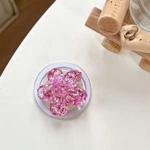 Close-up of glitter-filled pink floral Magnetic phone grip accessory on white surface
