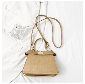 Détail du sac à main beige aspect crocodile avec fermoir rotatif doré élégant et raffiné