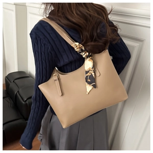 Detail of light brown leather tote bag with a decorative floral silk scarf on shoulder strap