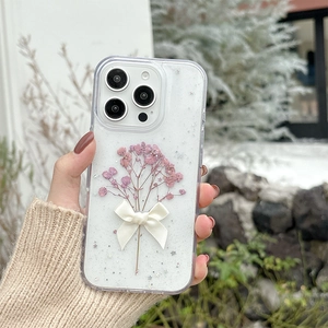 Detail of clear iPhone case with pink dried flowers, sequins, and a 3D silk bow