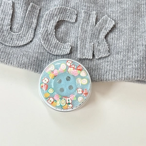 Close-up of a round magnetic phone grip with blue glitter and miniature fruit slices