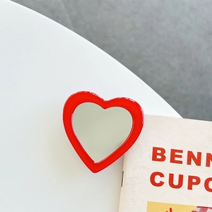 Close-up of heart-shaped red phone mirror bracket with a polished reflective surface
