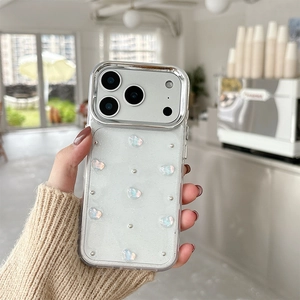 Dettaglio cover iPhone con cuori 3D iridescenti e perle argentate su cornice metallica
